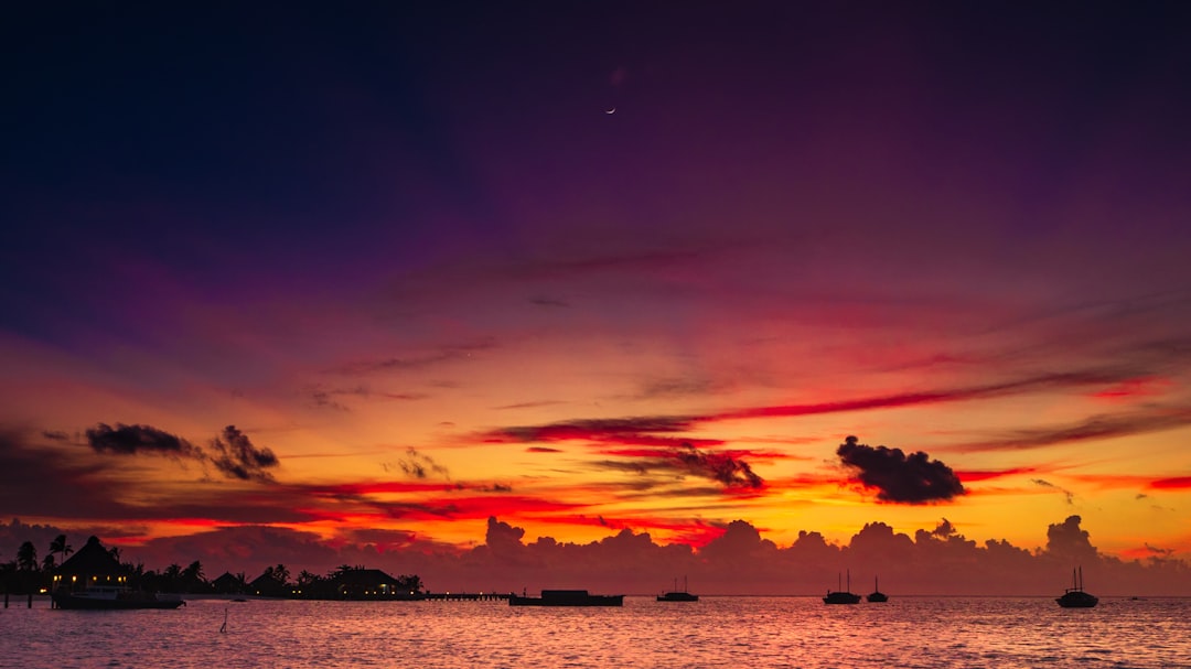 a colorful sunset over a body of water, Sunset Safari Island Maldives