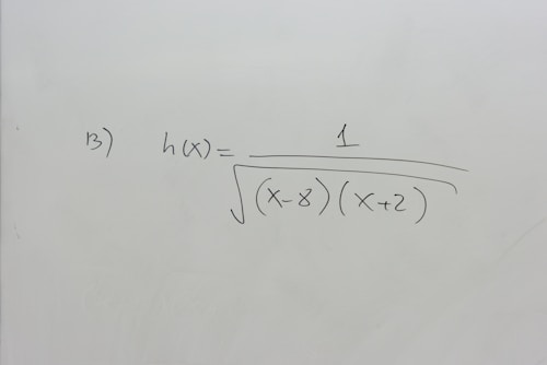 A section of a whiteboard features a mathematical expression written in black marker. The expression depicted is h(x) = 1 / &radic;((x-8)(x+2)), which suggests a function involving variables and parentheses. The board is otherwise clean, with no additional markings or annotations.