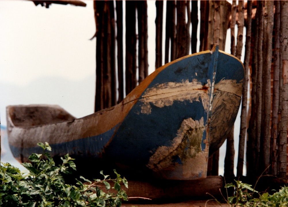 wrecked boat beside tree trunks