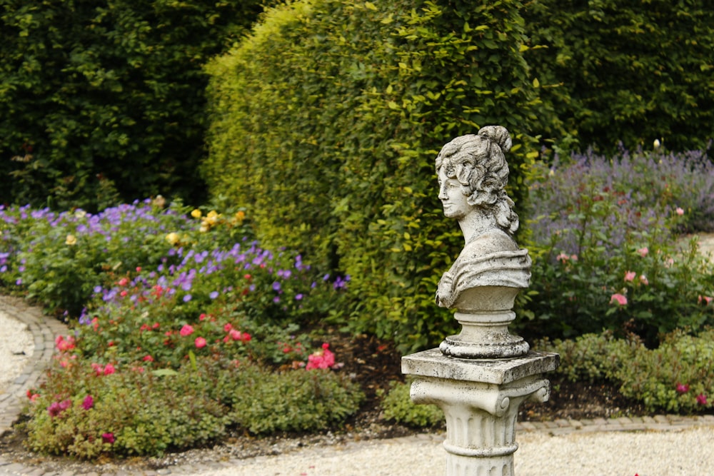 female face statue beside flower field