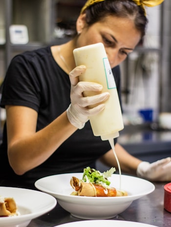 A chef carefully pouring sauce over a beautifully presented dish.