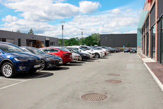 A row of well-maintained cars parked neatly in a lot with a cityscape background.