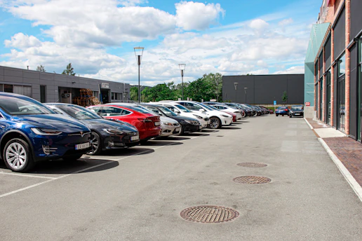 A row of well-maintained cars parked neatly in a lot with a cityscape background.