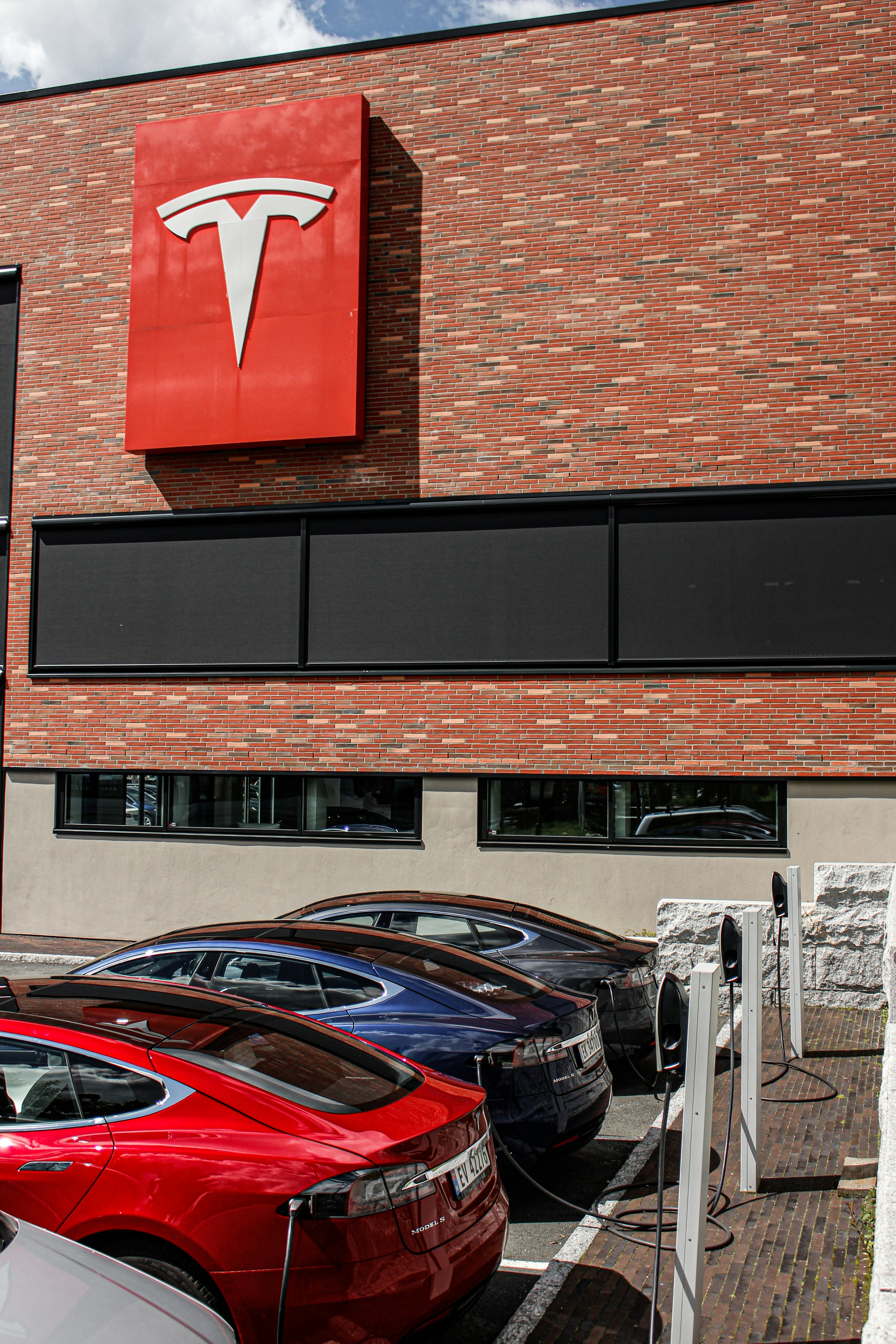 three red, blue, and black Tesla sedans