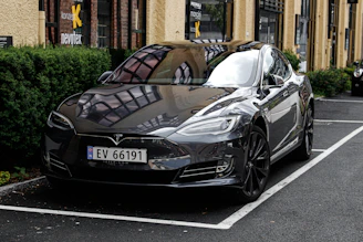A sleek black Tesla Model S parked in front of a modern building, ready for rental.