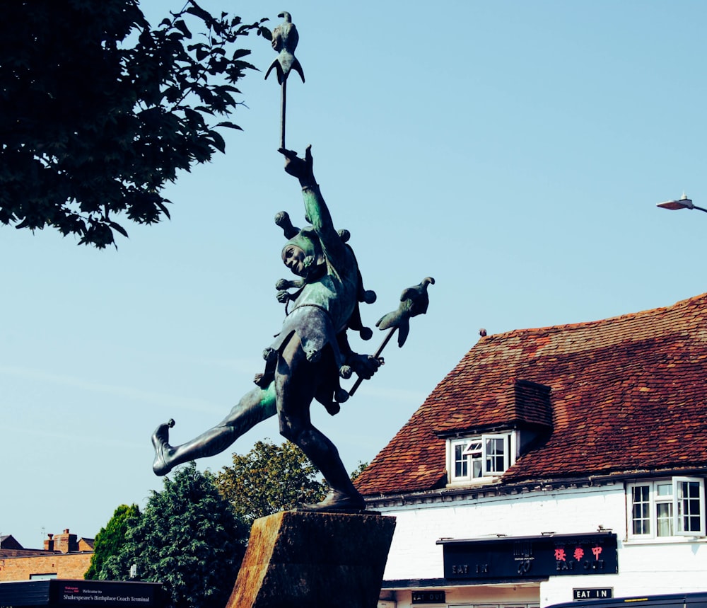 woman with birds statue near house during daytime