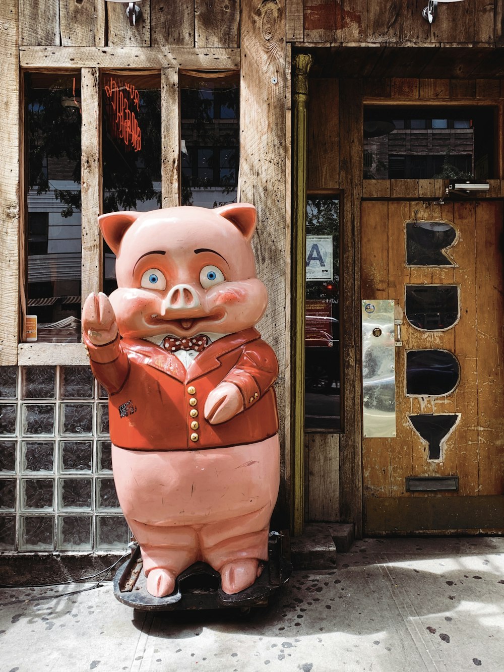 pink pig statue near brown wooden house