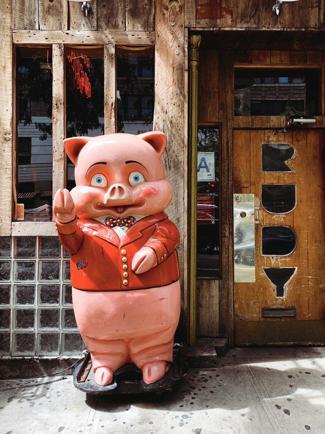 pink pig statue near brown wooden house