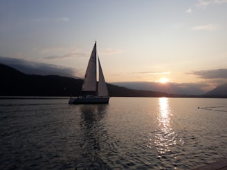A serene boat gliding on the crystal-clear waters of Lake Annecy at sunset.