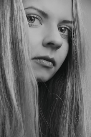 Elegant black and white portrait of a professional hairdresser examining hair texture under soft lighting.