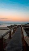 a wooden walkway leading to the beach at sunset