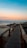 a wooden walkway leading to the beach at sunset