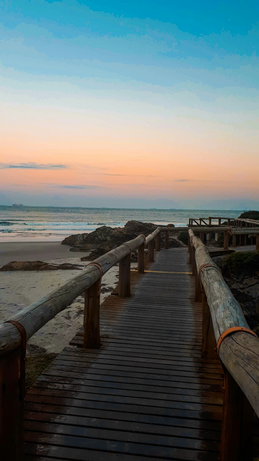 a wooden walkway leading to the beach at sunset