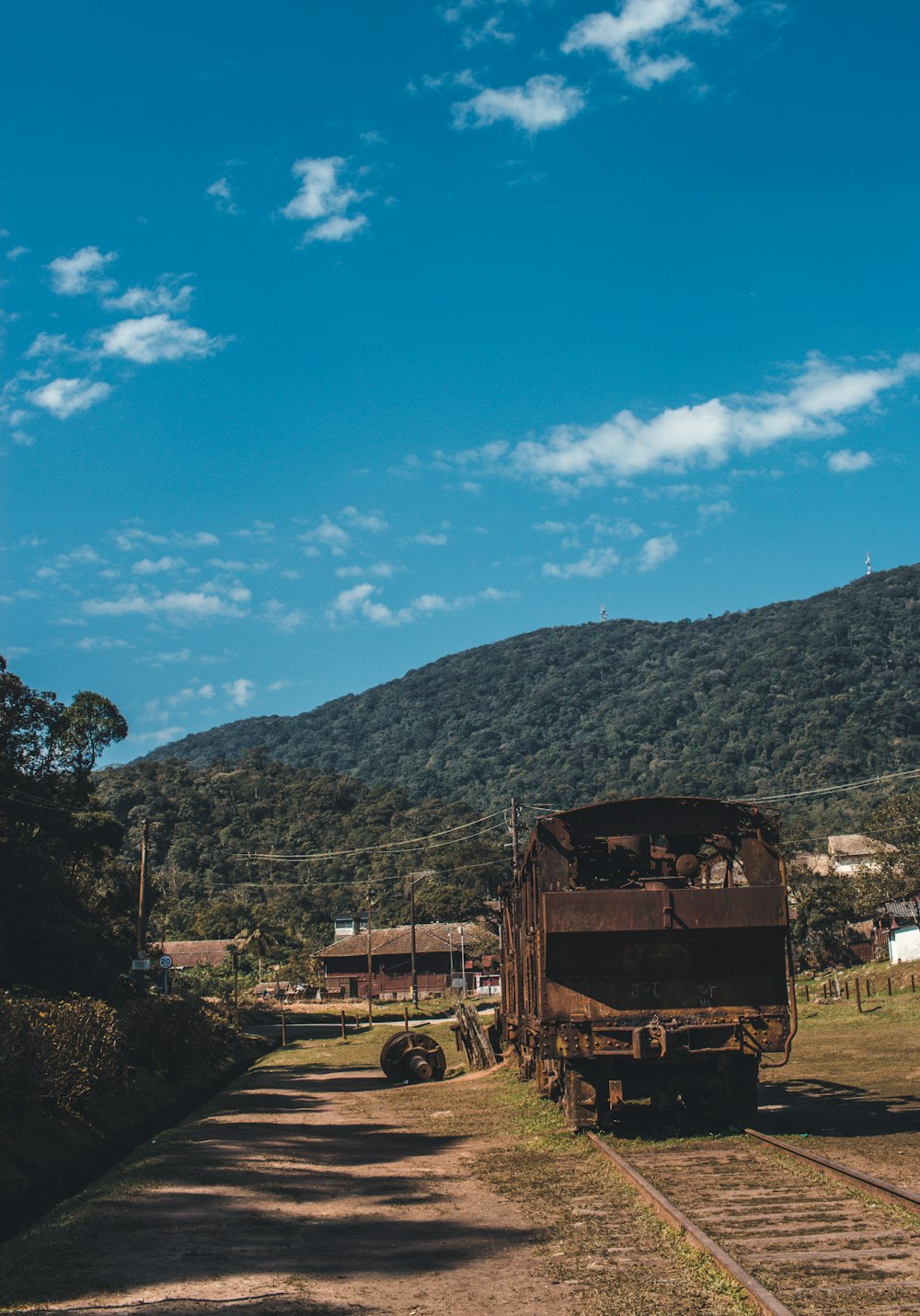 Camión marrón en la carretera cerca de las casas bajo cielos azules y blancos durante el día