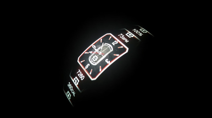 A digital smartwatch display is illuminated against a dark background. The screen features a digital clock with both analog and digital formats, including health metrics like step count, heart rate, and calorie count.