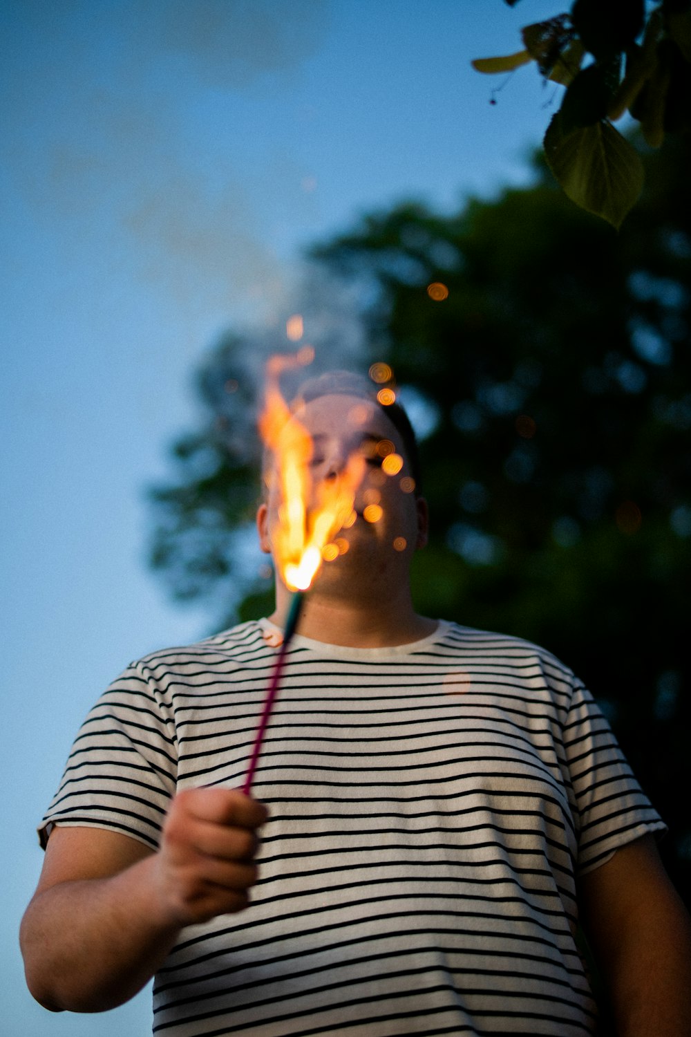 a man holding a stick with a fire in it