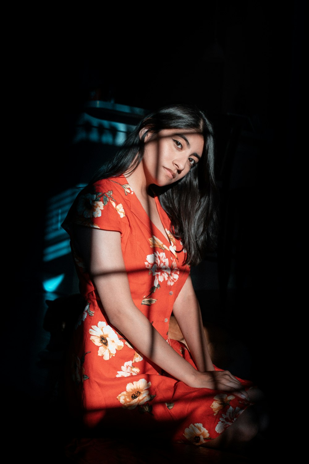 a woman in an orange dress sitting in the dark