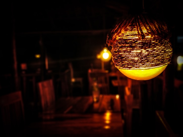 Close-up of a handcrafted recycled glass lamp glowing warmly in a dark room.