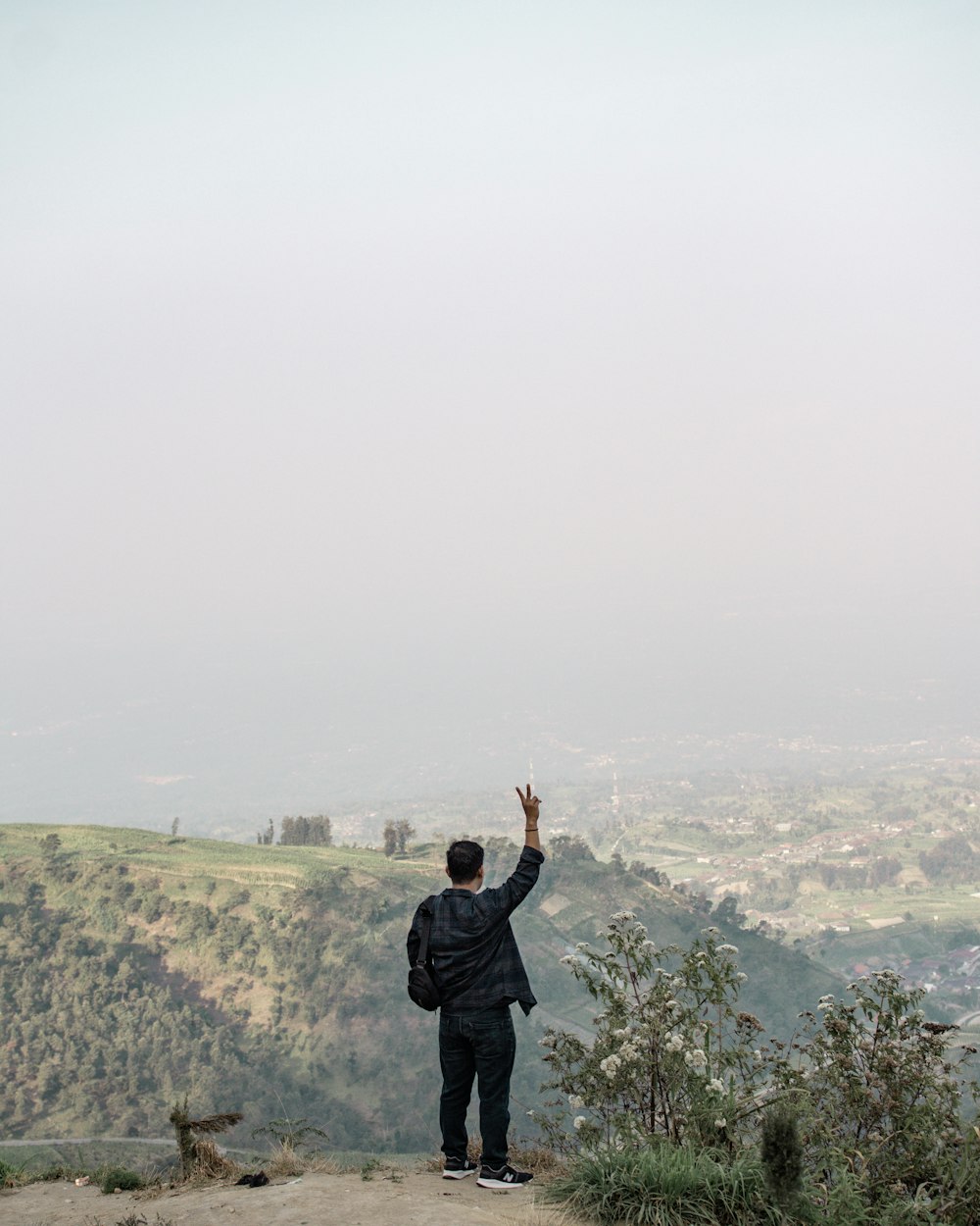 a man standing on top of a hill flying a kite