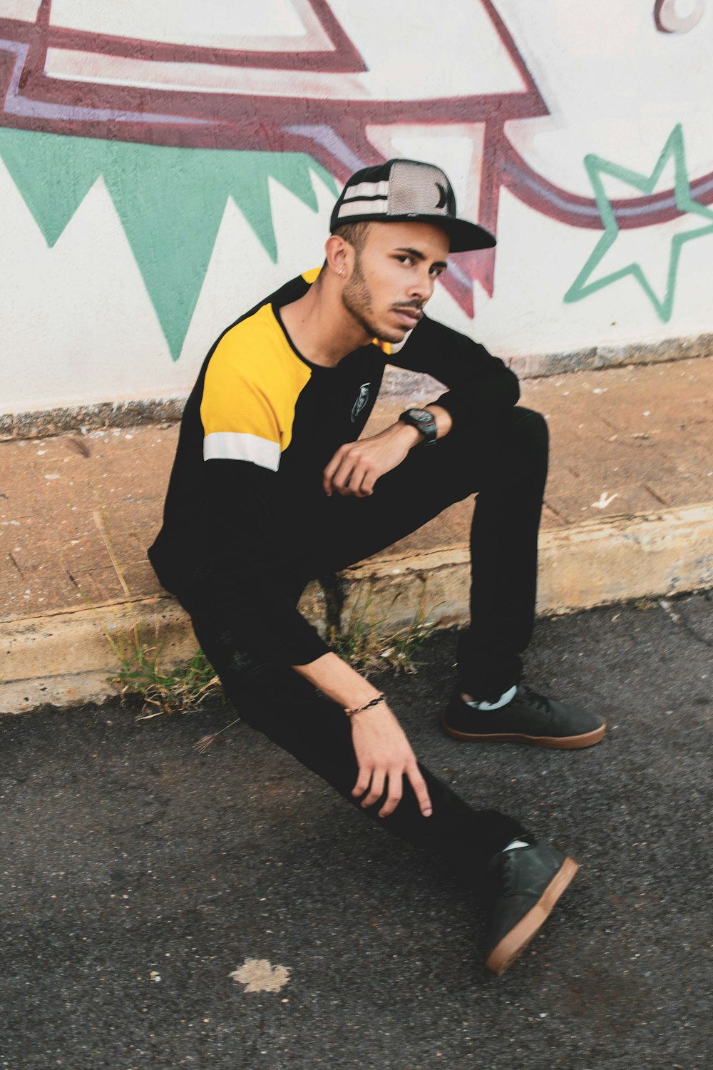 a man sitting on the ground in front of a wall