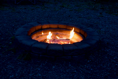 A beautifully designed stone patio with integrated fire pit glowing at dusk.