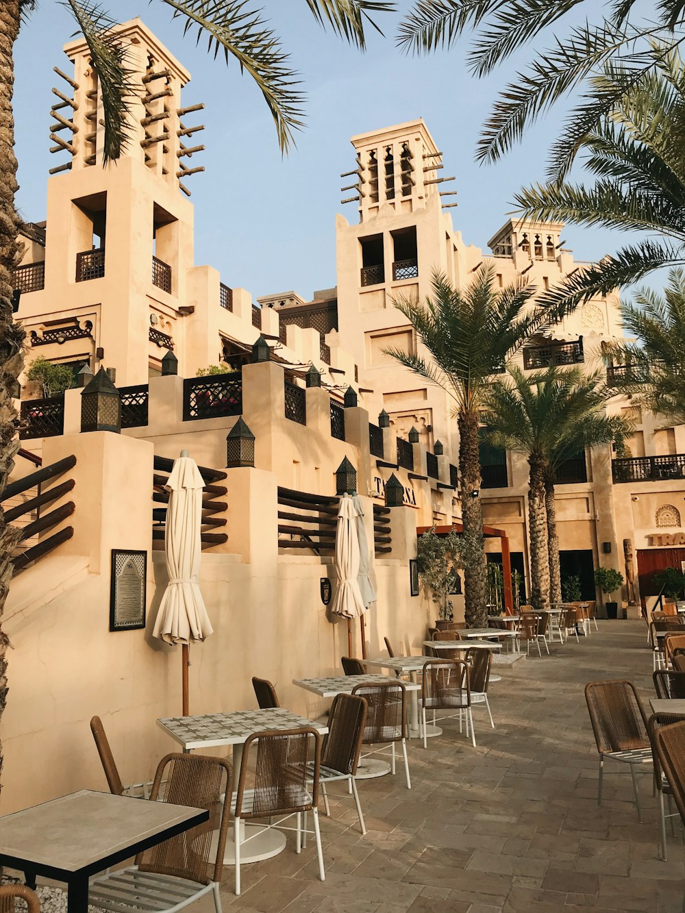 tables and chairs outside of a building with palm trees