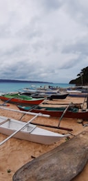 A sunlit beach in Sibale with clear turquoise waters and local fishermen preparing their boats at dawn.
