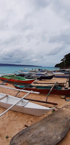 A sunlit beach in Sibale with clear turquoise waters and local fishermen preparing their boats at dawn.