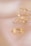 Close-up of a delicate gold personalized ring resting on a beige textured surface.