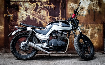 A cinematic shot of a vintage motorcycle parked beside a dimly lit, graffiti-covered wall.