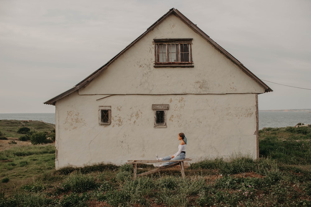 woman sitting on chair beside concrete house near body of water