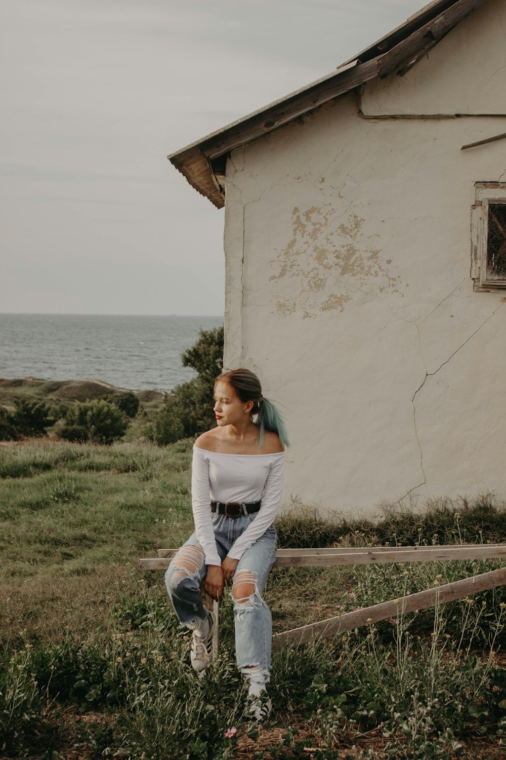 woman sitting on wooden frame front of house at daytime