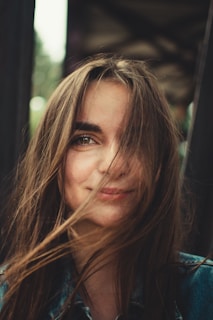 A young woman smiling with soft, loose curls framing her face.