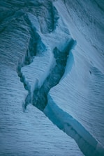 a large crack in the side of a snow covered mountain