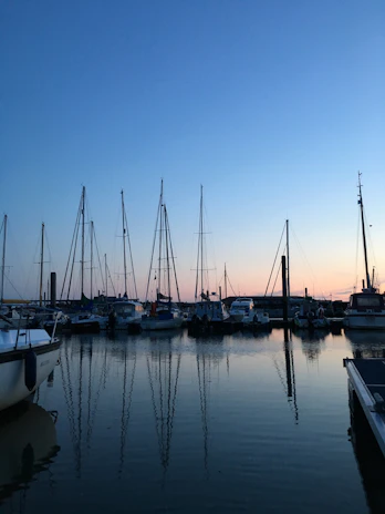 A serene harbor scene at dawn, showing vessels that PT. aurelia crewing management services.