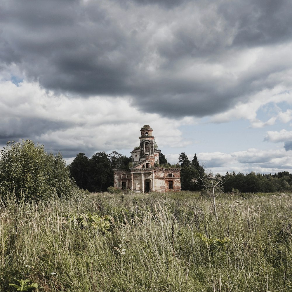 white and brown castle in green field surrounded with tall and green trees under gray and white skies during daytime