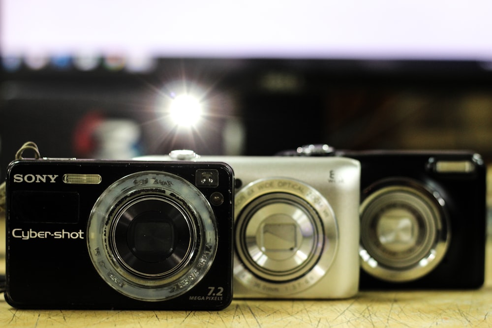 two black and one silver cameras