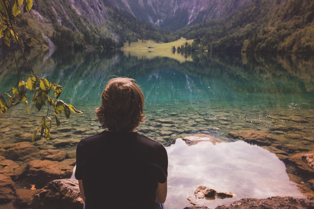 호수와 암석 근처에 앉아있는 사람