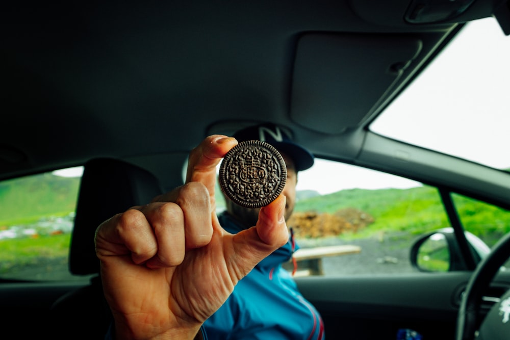 person holding round copper-colored coin