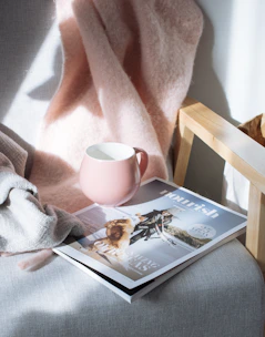 A cozy, high-resolution photo of a soft, folded blanket draped over a modern chair in natural light.