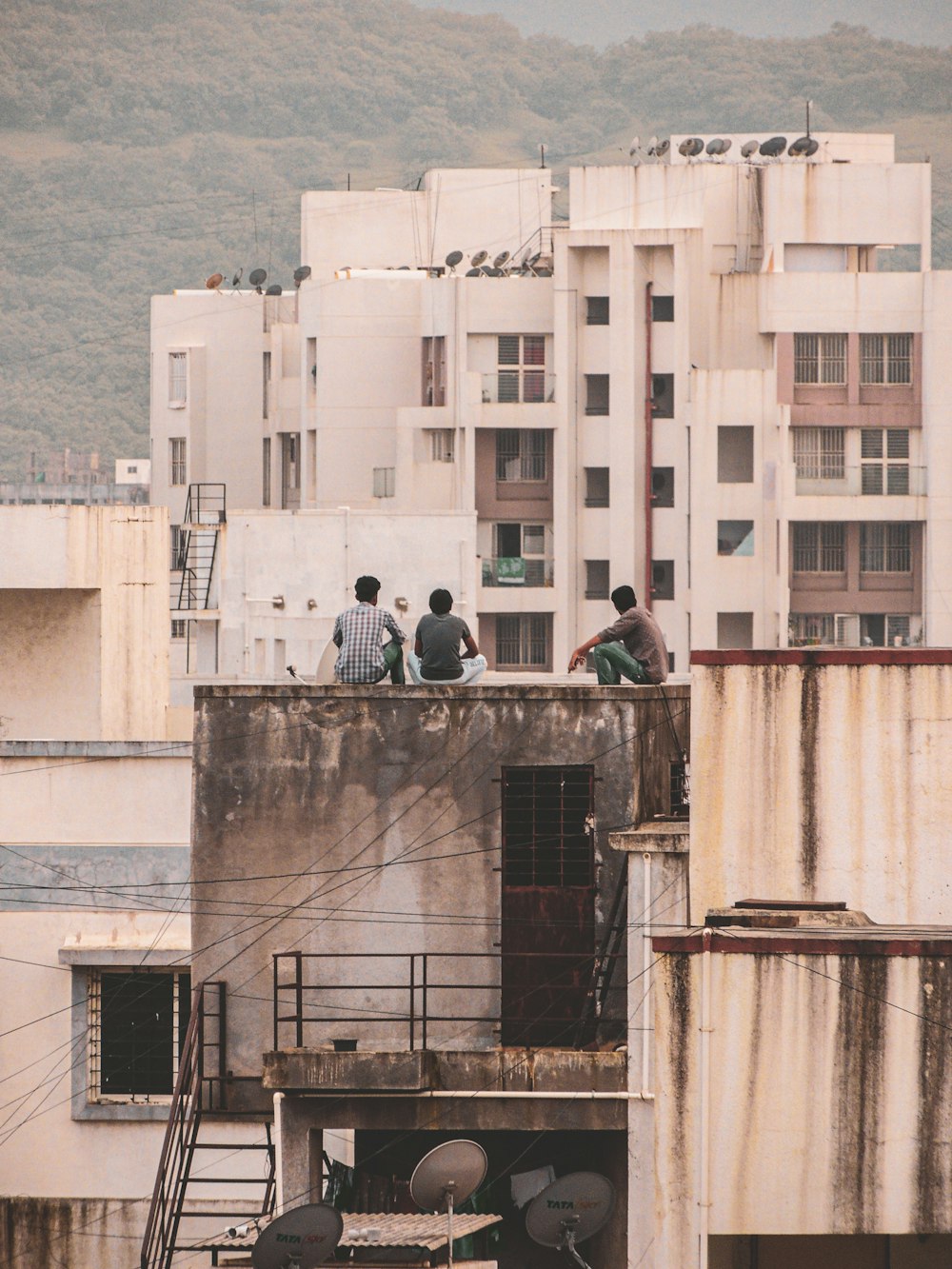 three men sitting on rooftop during daytime