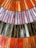 Colorful stained glass panel featuring elongated rectangular pieces arranged in rows. The glass pieces display a variety of colors including shades of orange, pink, purple, brown, and white, giving a vibrant and artistic look.