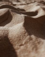 Fine sand particles form gentle, flowing dunes with soft shadows and highlights, providing a sense of calm and tranquility.