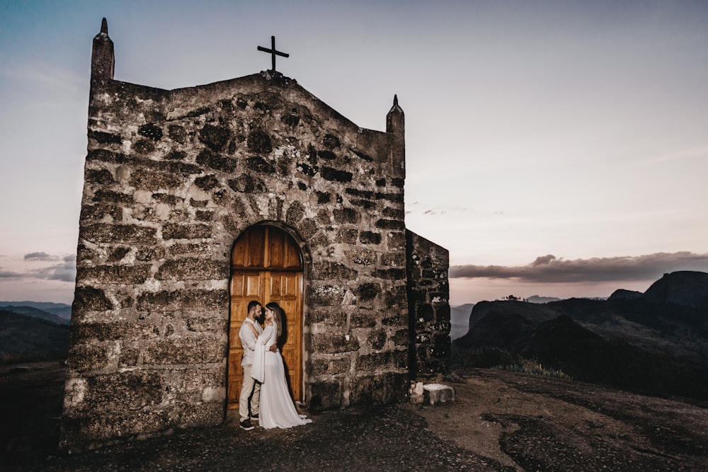 couple standing beside black concrete chapel