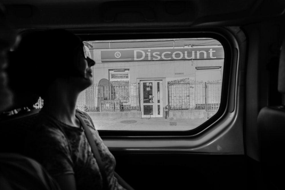 Photographie en niveaux de gris d’une femme à l’intérieur d’un véhicule