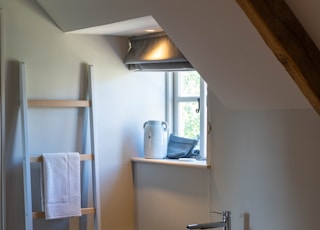 wooden ladder rack near white and black ceramic bathtub