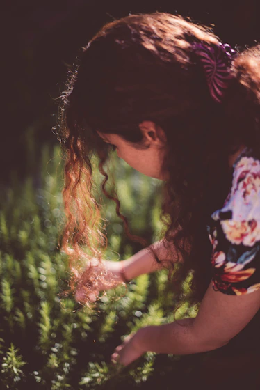 a woman bending down to pick up some flowers