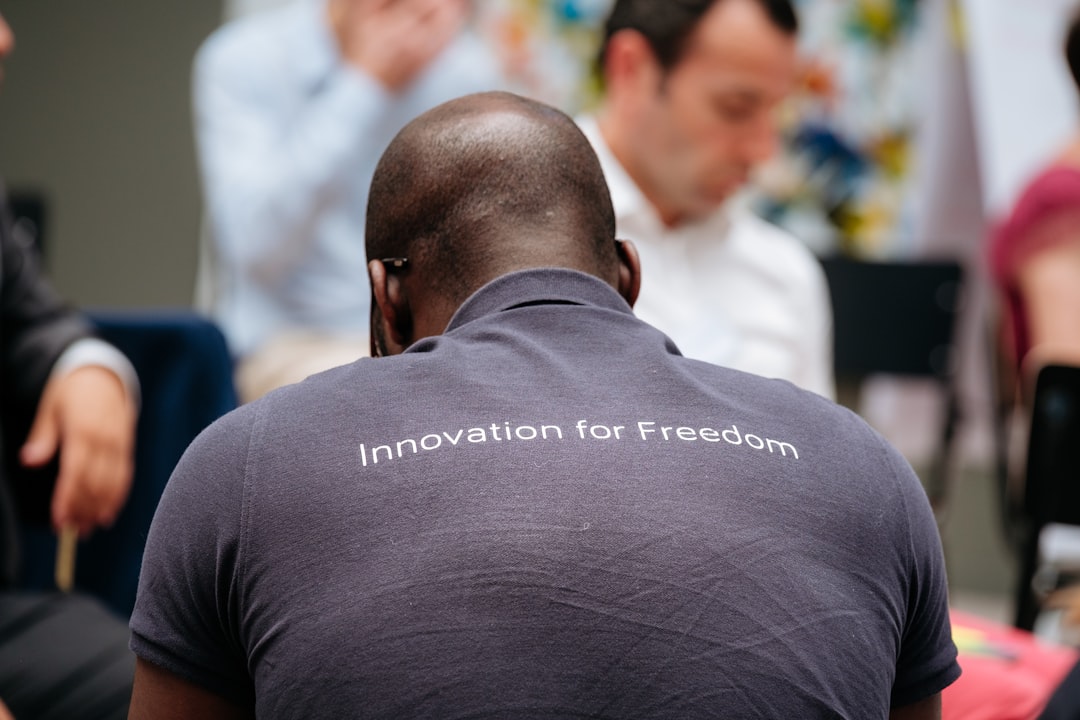 man wearing gray innovation for freedom print collared shirt near people,