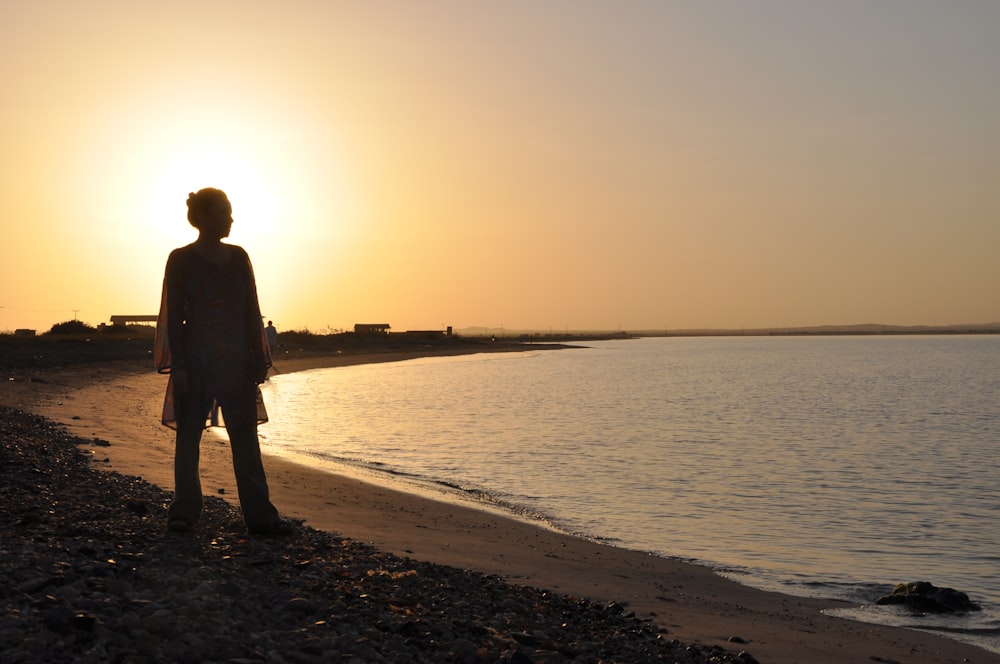 a person standing on a beach at sunset