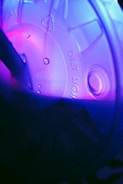 A close-up view of a translucent plastic lid with the words 'diet light' stamped on it. The lid is illuminated by pink and purple lighting, creating a vibrant and abstract visual effect. Water droplets are visible on the surface, adding texture and interest to the composition.